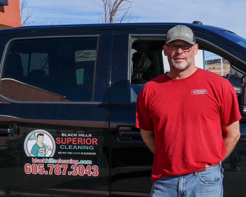 Carpet Cleaning expert Jon standing in front of his truck. The Black Hills Carpet Cleaning logo can be seen on the rear door.