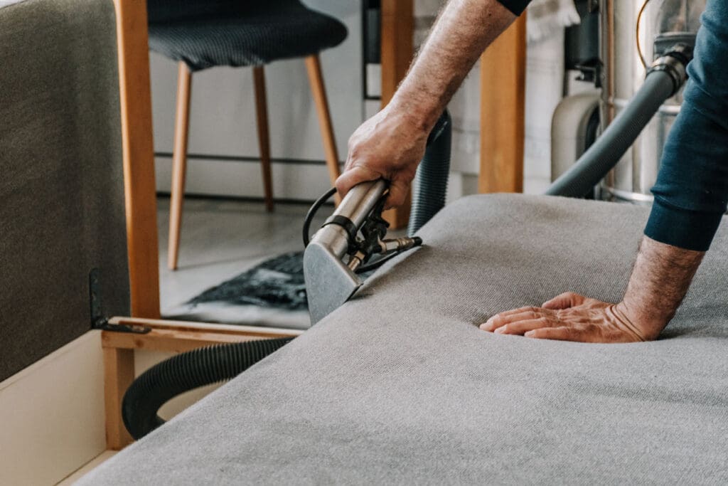 A full-service carpet cleaner restores a sofa using upholstery cleaning.